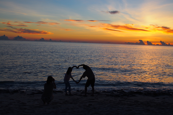 夕焼けに向かって、思い思いのポーズで写真を撮る人たち